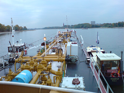 Holzkutter und zwei kleine Boote haben an einem Binnenschiff angelegt.