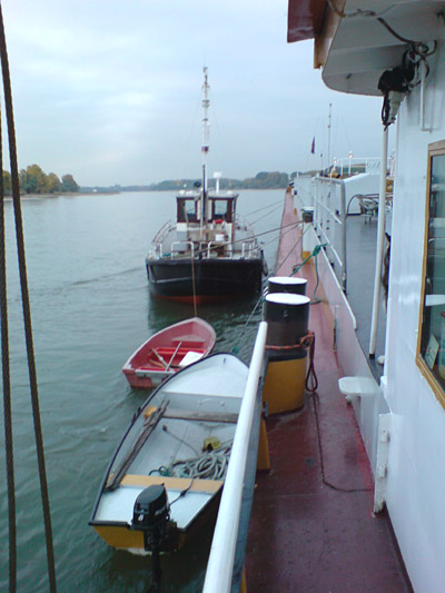 Holzkutter und zwei kleine Boote haben an einem Binnenschiff angelegt.