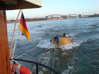 Stahlnachen am Tau am Heck von Noortje, auf dem Rhein vor einer Kölner Brücke.