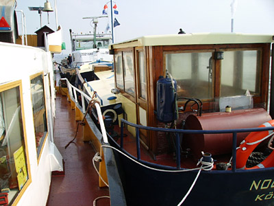 Bilgeboot und historisches Boot auf Seite vom Binnenschiff.