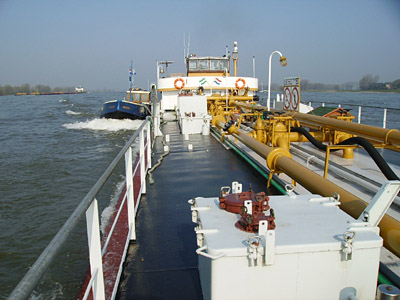 Perspektivisch riesiges Tankbinnenschiff, ganz weit hinten ein kleines Boot.